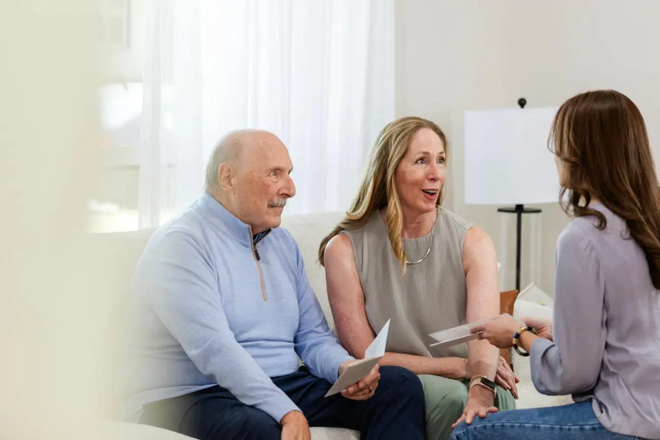 A nurse leads a guided conversation with an adult child and her father about senior care options.